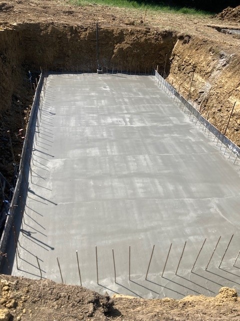 Radier béton ferraillé d'une piscine en cours de construction avec fers en attente