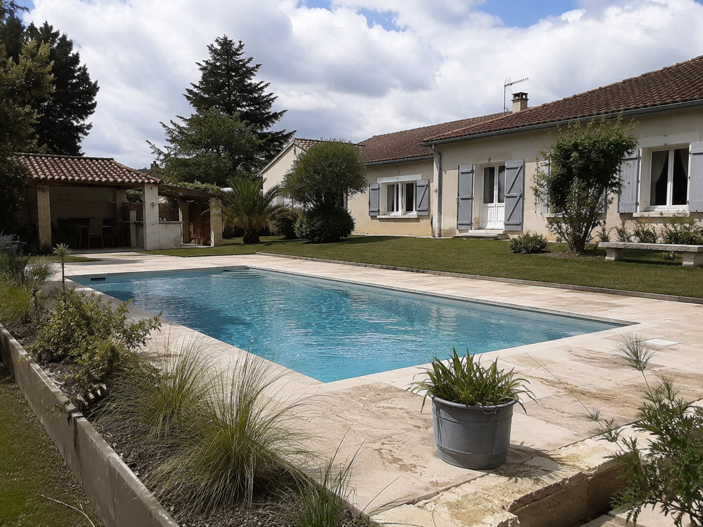 Piscine béton réalisée par Bati Aquitaine avec plage en pierre naturelle
