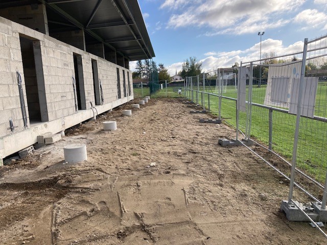 Bâtiment tertiaire en construction avec murs en agglos en bordure de stade