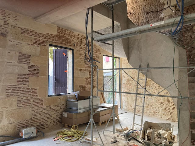Rénovation intérieure d'un bâtiment ancien : rejointement de murs en pierre avec échafaudage